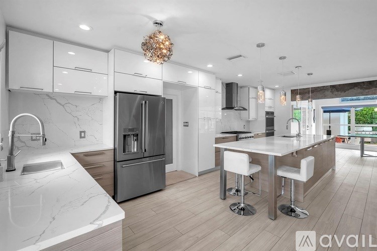 A modern kitchen with a marble countertop and stainless steel appliances.