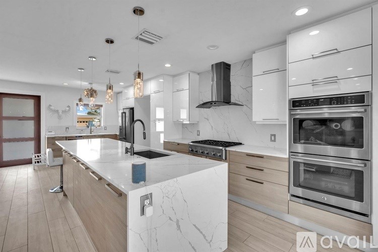 A modern kitchen with a marble countertop and stainless steel appliances.
