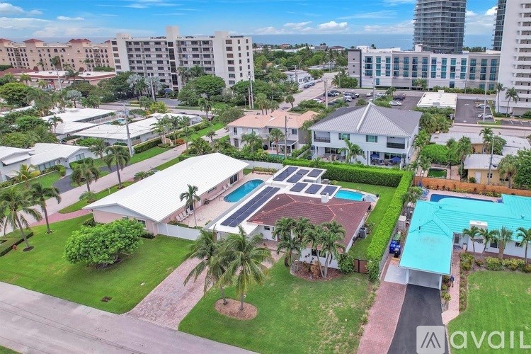 A large white building with a pool in the middle of a grassy area.