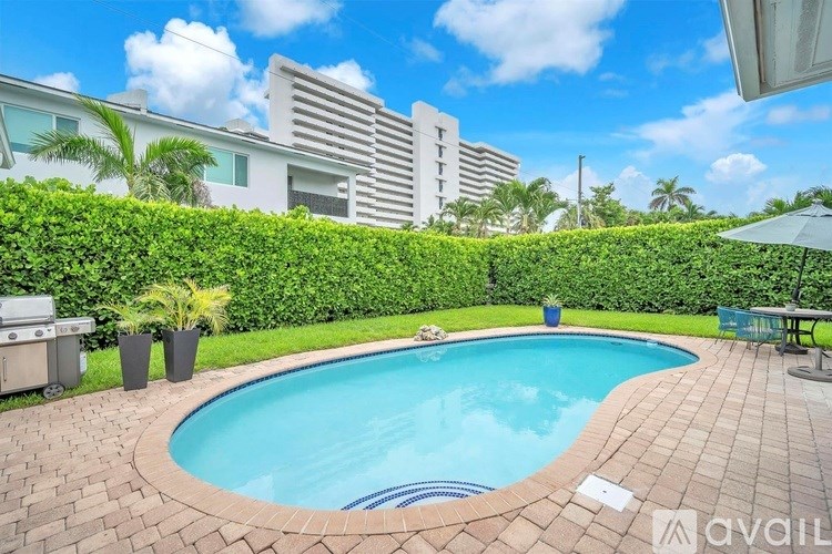 A pool surrounded by a brick border and a hedge.