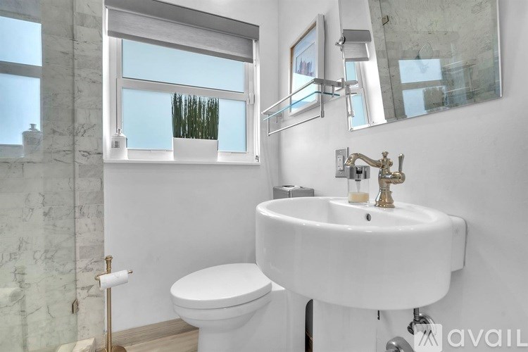 A bathroom with a white toilet, sink, and a window.