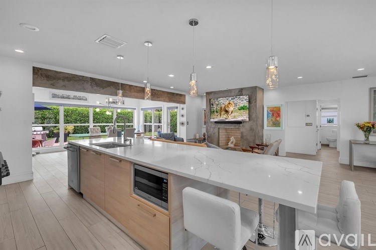 A modern kitchen with a large island and white chairs.