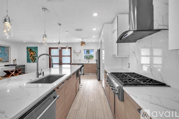 A modern kitchen with a marble countertop and wooden cabinets.