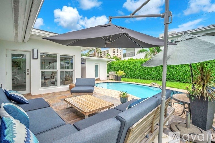 A sunny day at the poolside with a wooden table and chairs.