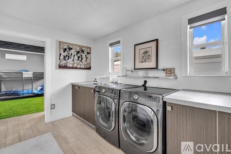 A laundry room with a washer and dryer, a window, and a framed picture on the wall.
