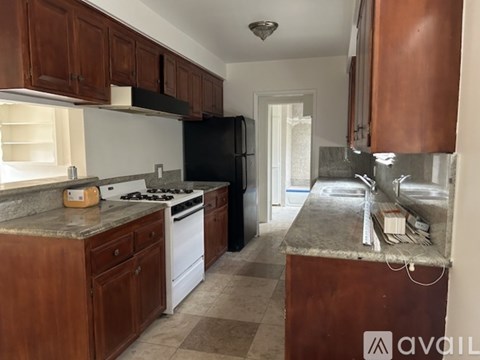 A kitchen with brown cabinets and a black refrigerator.