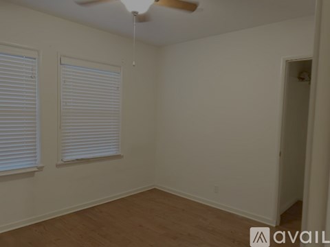 A room with a ceiling fan and two windows with blinds.