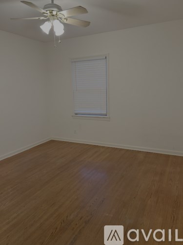 A room with a ceiling fan and wooden flooring.