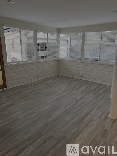 A room with wooden flooring and white walls.