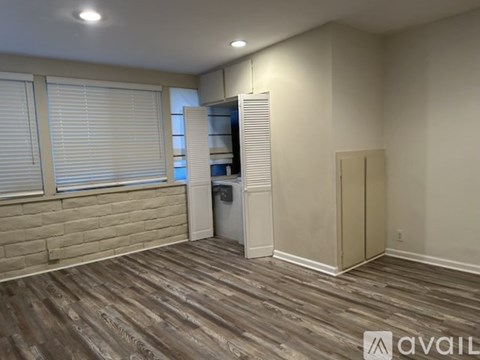 A room with wooden flooring and a white refrigerator.
