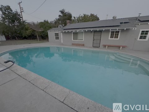 A pool in a backyard with a house in the background.