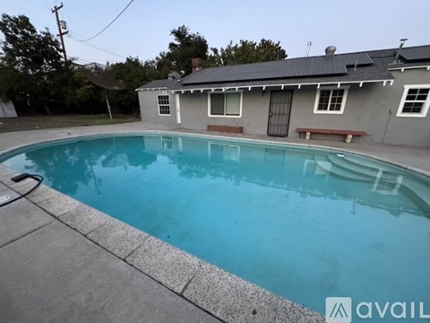 A pool in a backyard with a house in the background.