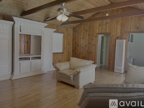 A living room with wooden walls and a ceiling fan.