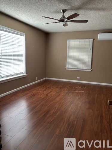 A room with a ceiling fan and wooden flooring.