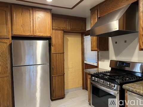 A kitchen with wooden cabinets and a stainless steel refrigerator.
