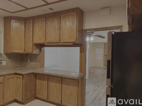 A kitchen with wooden cabinets and a black refrigerator.