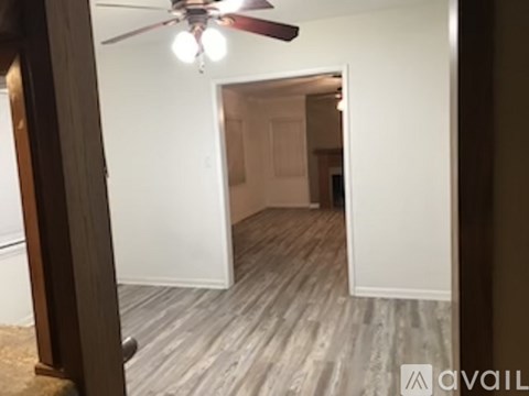 A room with a ceiling fan and wooden flooring.