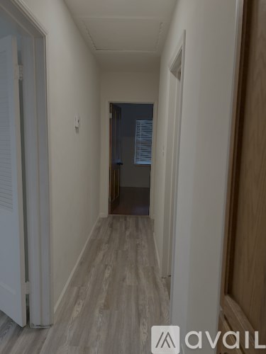 A hallway with a wooden floor and white walls.