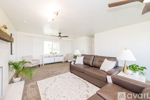 A living room with a brown couch and a white rug.