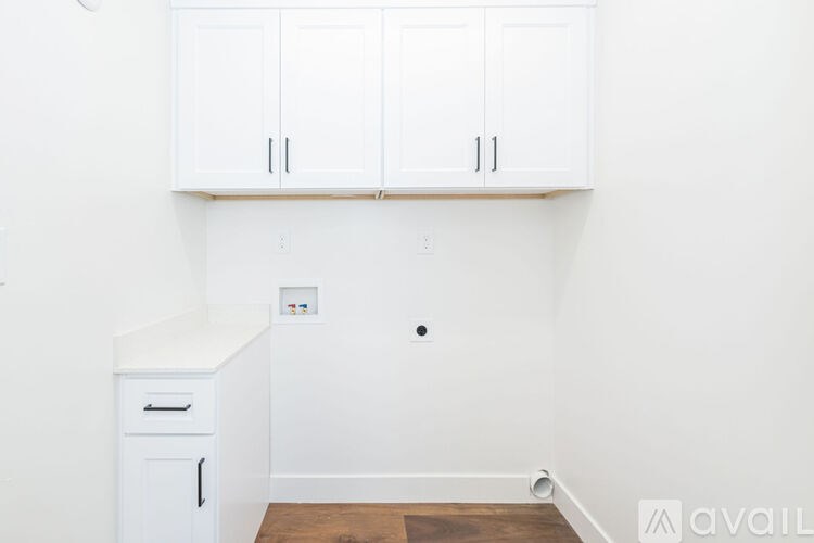 A white cabinet with a drawer is on the left side of a white wall.