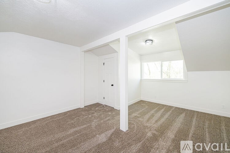 A carpeted room with a window and a door.