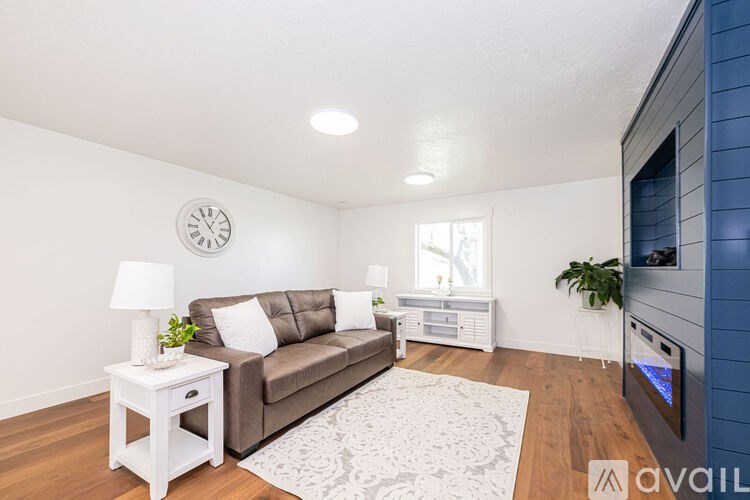 A living room with a brown couch, a white side table, and a television.