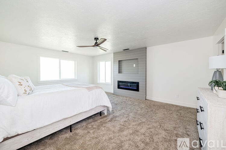 A bedroom with a bed, a ceiling fan, and a fireplace.