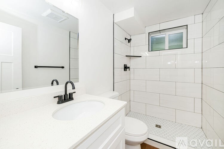 A white bathroom with a toilet, sink, and shower.