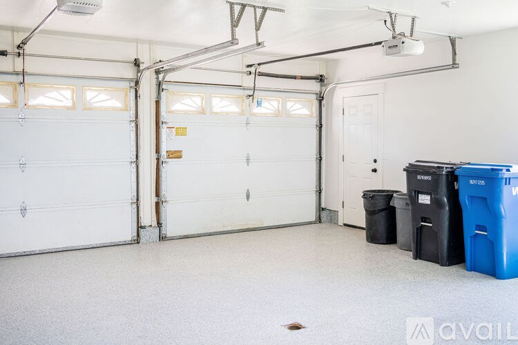 A large empty garage with two doors and a few bins.