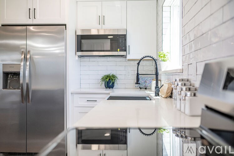 A modern kitchen with a stainless steel refrigerator and white cabinets.