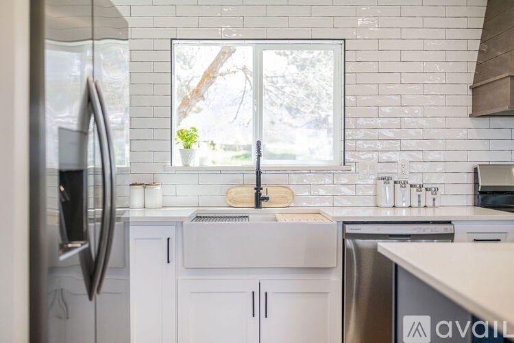 A kitchen with white cabinets and a window showing a tree outside.