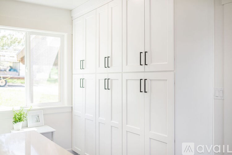 A white cabinet with black handles is in a room.
