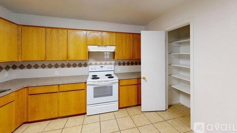 A kitchen with wooden cabinets and a white stove top oven.