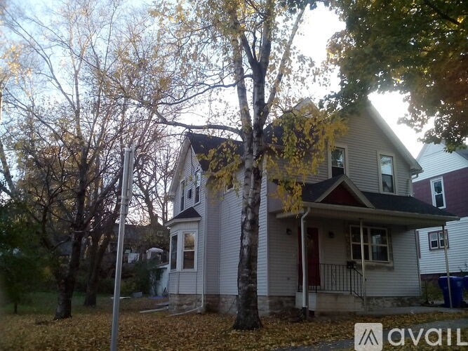 A house with a porch and a tree in front of it.