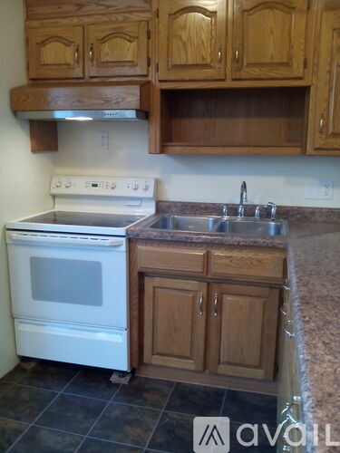 A kitchen with a white oven and wooden cabinets.