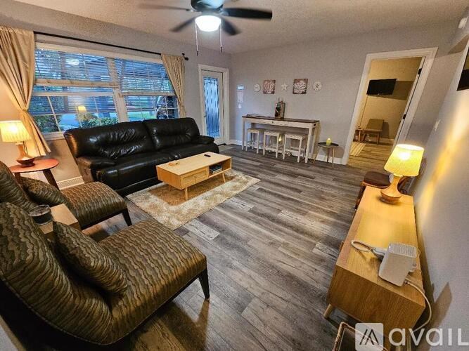 A living room with a black leather couch, a brown armchair, and a wooden coffee table.