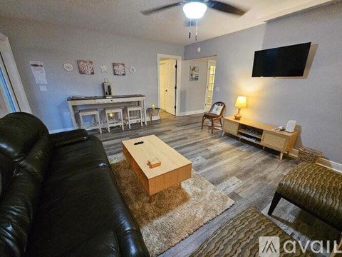 A living room with a black leather couch and a wooden coffee table.