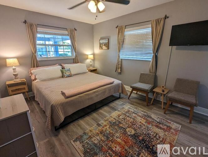 A bedroom with a large bed, a chair, and a rug.