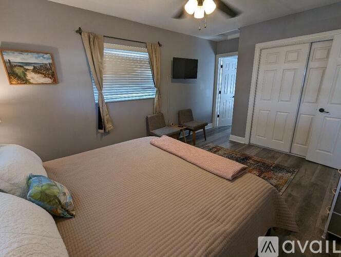 A bedroom with a bed, a chair, and a television.