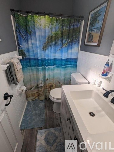 A bathroom with a beach scene shower curtain.