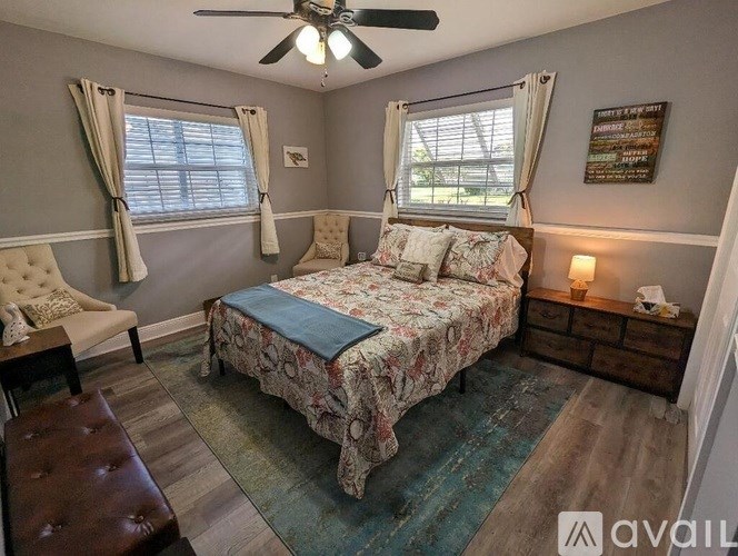 A bedroom with a bed, chair, and window.