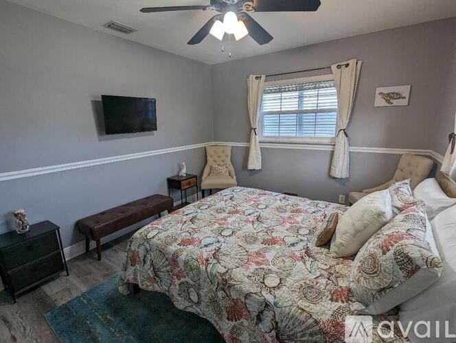 A bedroom with a bed, bench, and television.