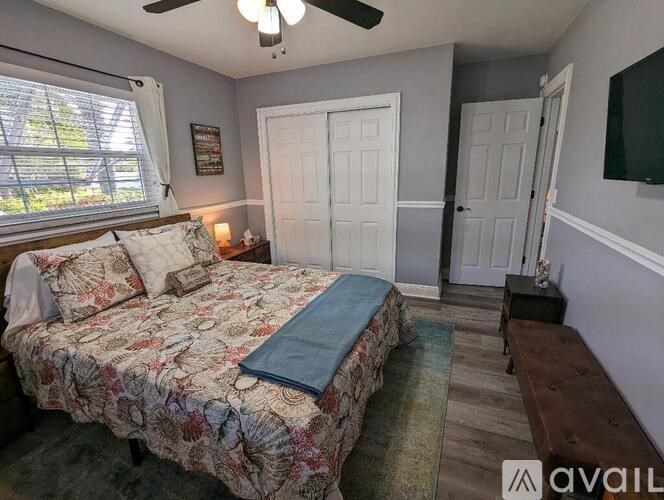 A bedroom with a bed, a ceiling fan, and a window with blinds.