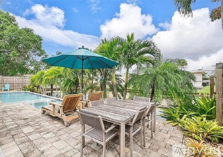 A patio with a table and chairs overlooking a pool.