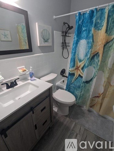 A bathroom with a white sink, toilet, and a shower curtain with a starfish design.