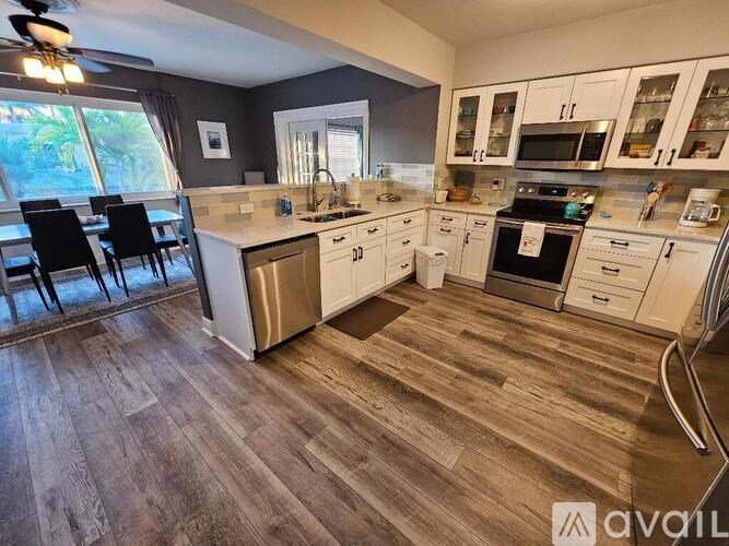 A kitchen with white cabinets and a wooden floor.
