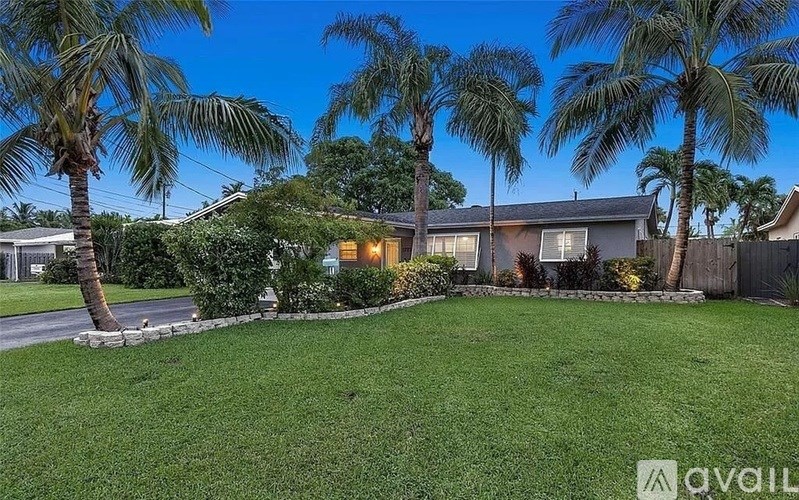 A house with a lawn and palm trees in front.