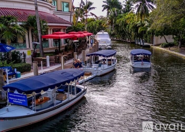 A boat with a blue canopy is docked in a canal with other boats.