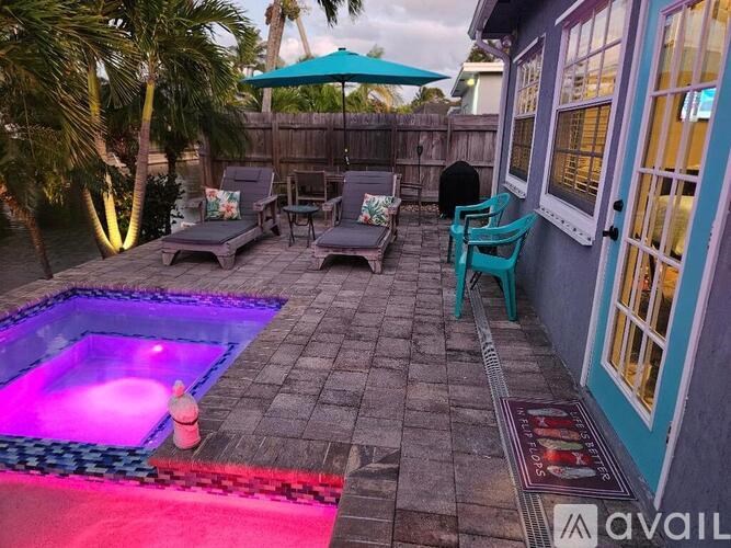 A patio with a hot tub and chairs.