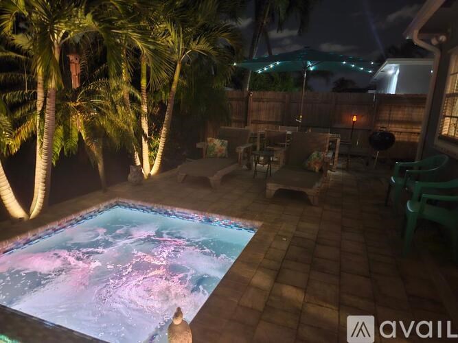 A pool with a waterfall in the middle of a backyard.